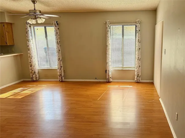 an empty room with wooden floor and windows