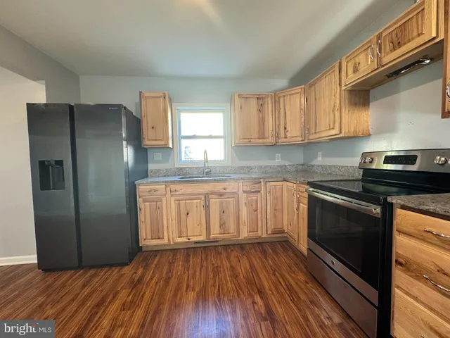 a kitchen with granite countertop wooden floors stainless steel appliances and a window