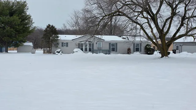 a front view of a house with a yard covered in snow