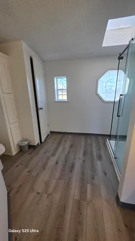 a view of an empty room with wooden floor and a window