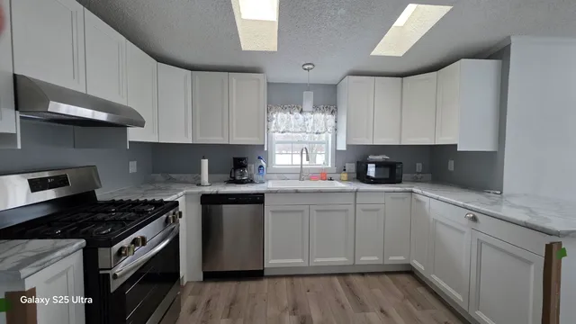 a kitchen with granite countertop white cabinets and appliances