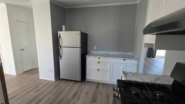 a kitchen with a refrigerator and wooden floor