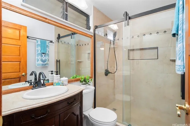 a bathroom with a sink vanity granite toilet and shower