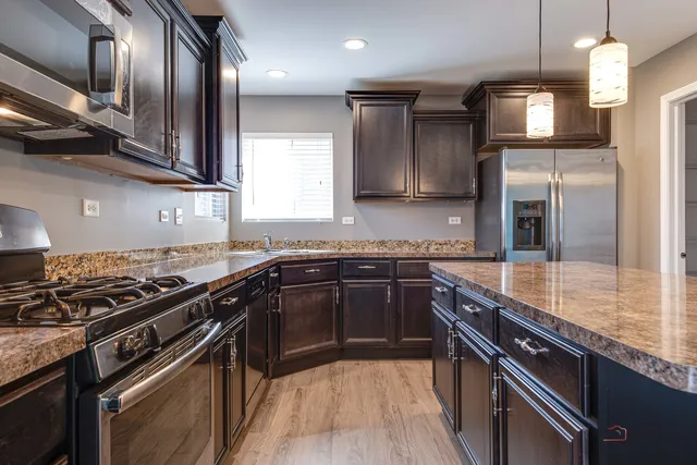 a kitchen with stainless steel appliances granite countertop a sink a stove and a refrigerator