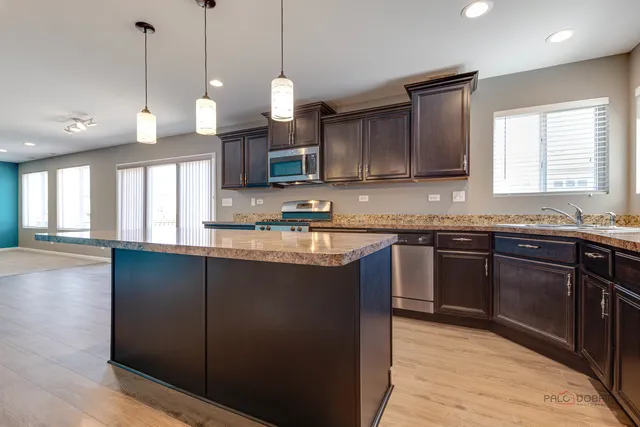 a kitchen with stainless steel appliances granite countertop a sink a stove a refrigerator and a microwave