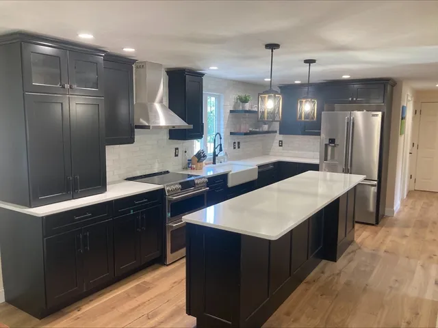a kitchen with stainless steel appliances kitchen island granite countertop a sink and a refrigerator