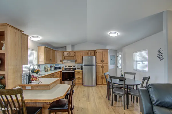 a kitchen with stainless steel appliances a dining table chairs and a refrigerator