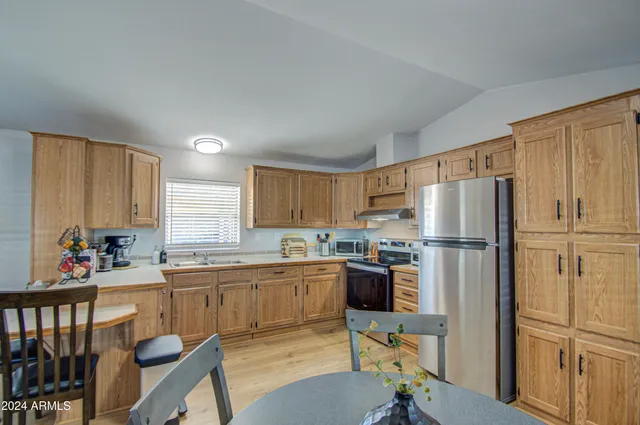 a kitchen with stainless steel appliances a refrigerator a sink a stove a table and chairs