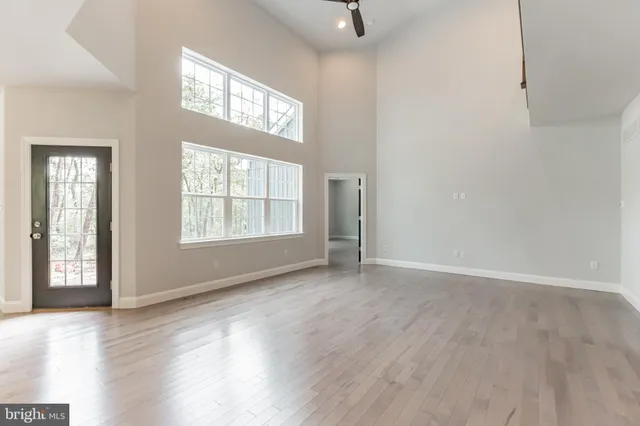 an empty room with wooden floor cabinet and windows