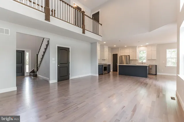 a view of a hallway with wooden floor and a kitchen
