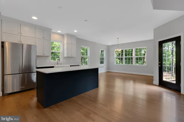 a kitchen with stainless steel appliances granite countertop a refrigerator a sink and a stove with wooden floor