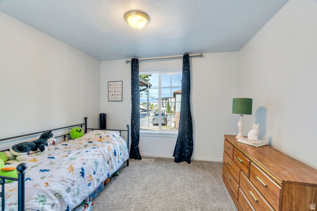 1727 South Sandhill Road Orem, UT 84058 - Photo 20 of 27 Neutral wall paint, plush carpet flooring, and a single window with dark curtains define this bright room