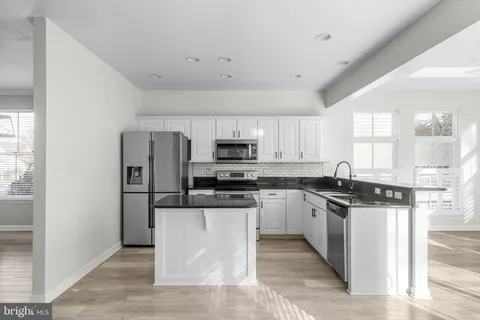 a kitchen with stainless steel appliances granite countertop a stove top oven a refrigerator a sink and dishwasher with wooden floor