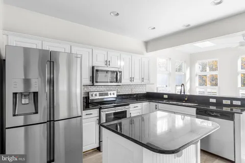 a kitchen with stainless steel appliances granite countertop a sink a stove and a refrigerator