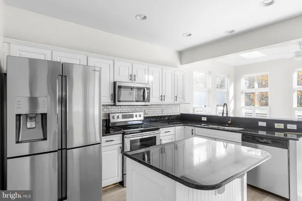 a kitchen with stainless steel appliances granite countertop a sink a stove and a refrigerator