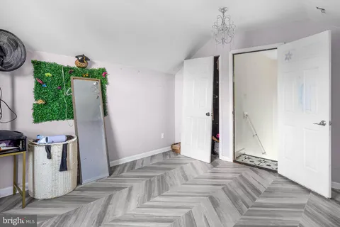a view of an empty room with wooden floor and a ceiling fan