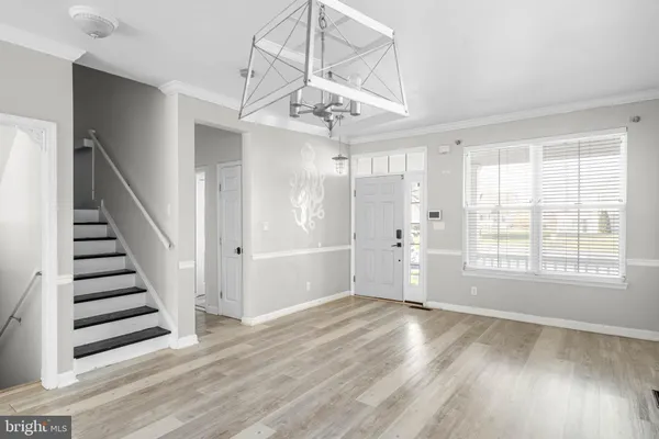 a view of an empty room with wooden floor and fan