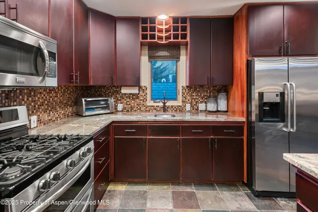 a kitchen with kitchen island granite countertop a sink stainless steel appliances and cabinets