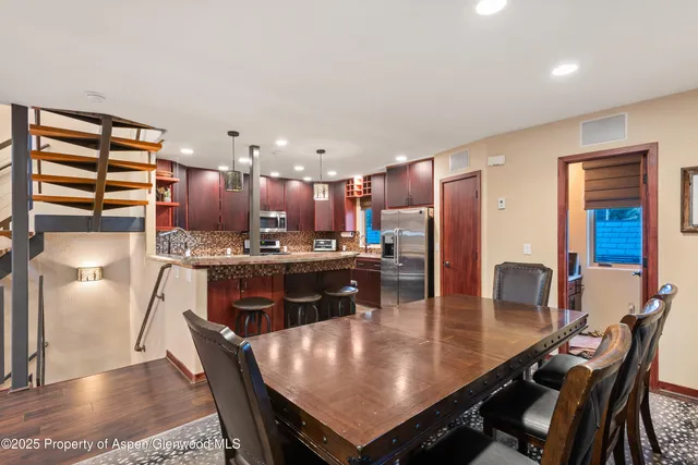 a kitchen with a dining table chairs and refrigerator