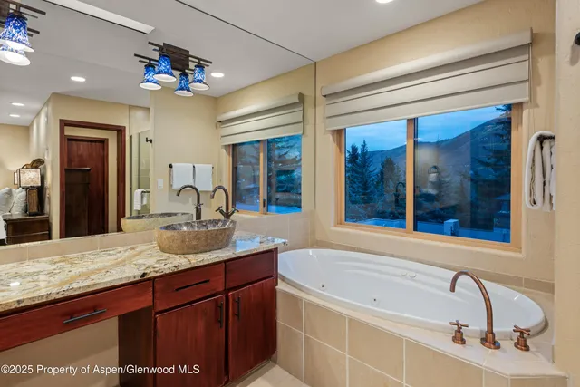 a bathroom with a granite countertop sink a large mirror and a bathtub