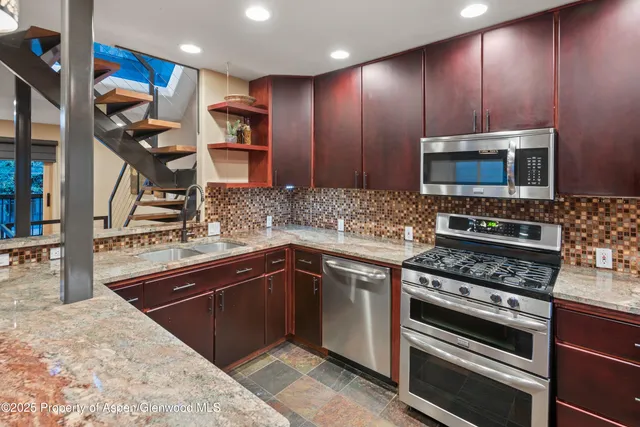 a kitchen with stainless steel appliances kitchen island granite countertop a stove and a sink