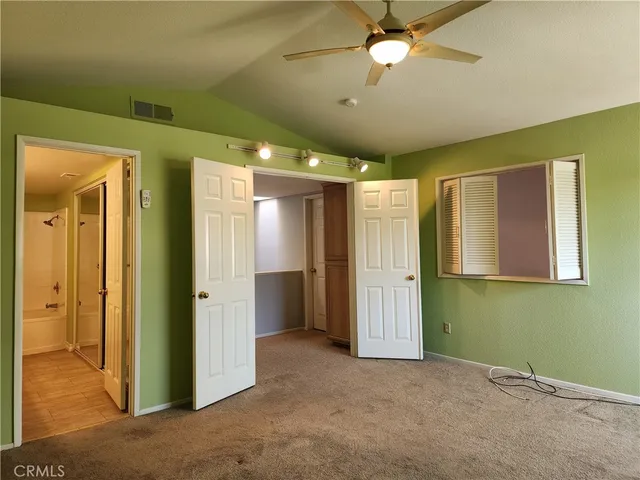 an empty room with closet and a chandelier fan