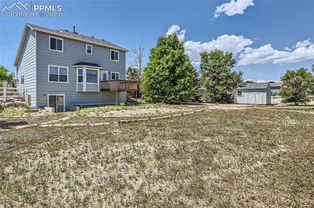 12510 Motley Road Peyton, CO 80831 - Photo 28 of 36 Rear view of house featuring a shed, a deck, and a lawn