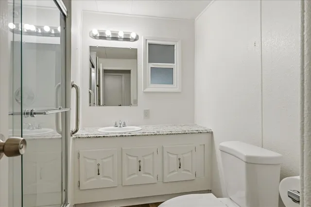 a bathroom with a granite countertop shower and a sink