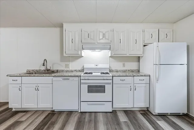 a kitchen with granite countertop white cabinets and white appliances