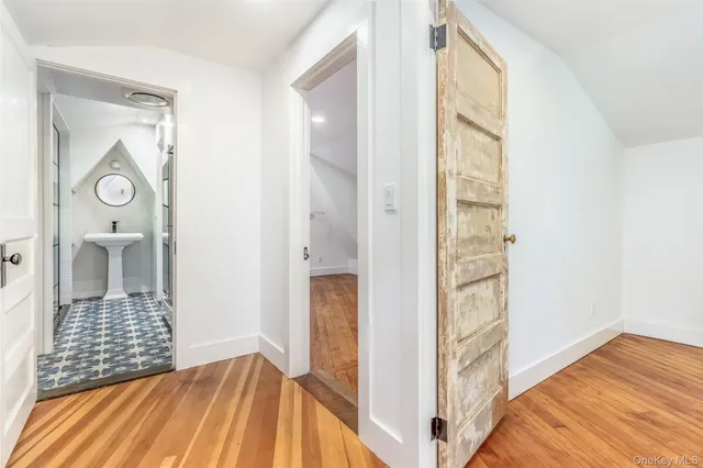 a view of a hallway with wooden floor and a bathroom
