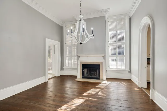 a view of an empty room with wooden floor fireplace and a window