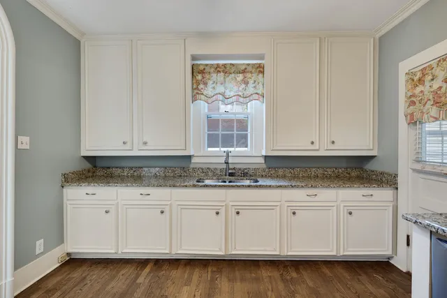 a kitchen with granite countertop white cabinets and sink