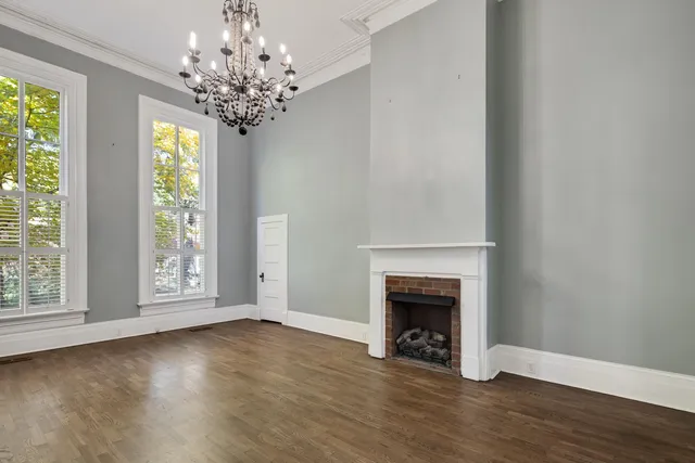 a view of an empty room with wooden floor fireplace and a window