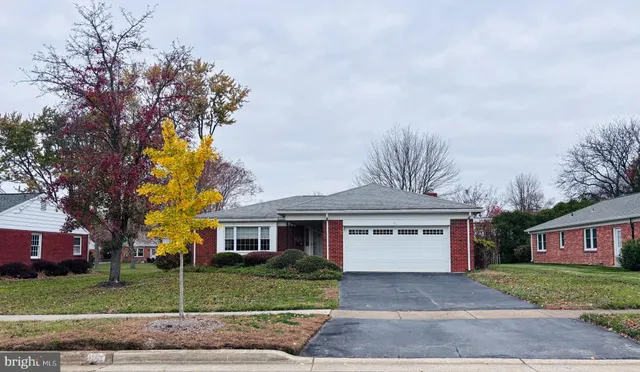 a front view of a house with a garden and trees