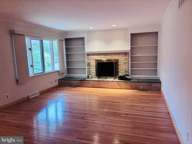 a view of empty room with wooden floor and fireplace