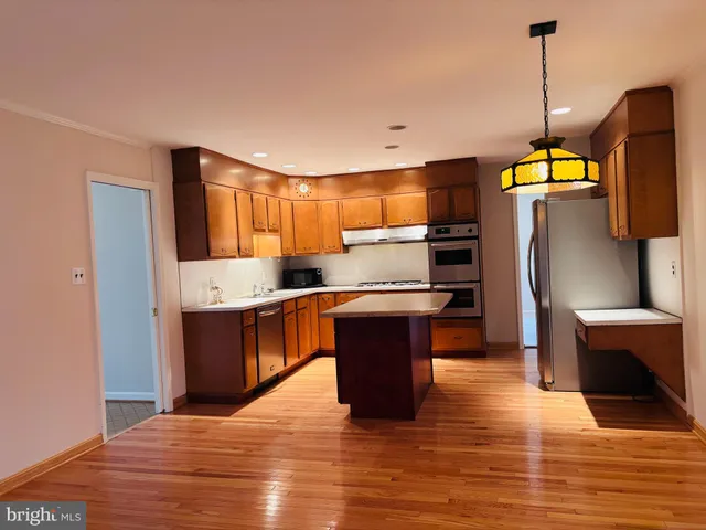 a kitchen with stainless steel appliances granite countertop a refrigerator a sink dishwasher a stove and white countertops with wooden floor