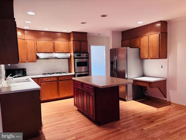a kitchen with stainless steel appliances wooden floors and wooden cabinets