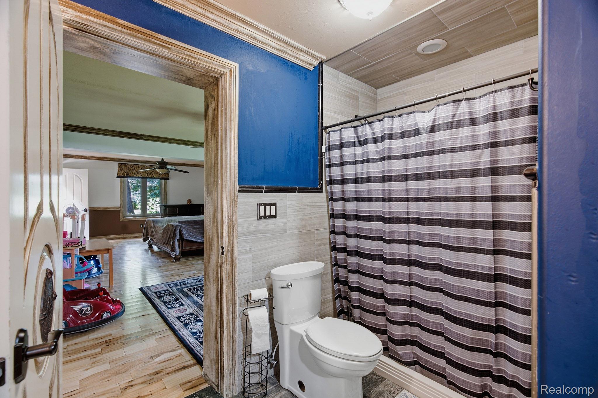 1258 Priscilla Lane Rochester, MI 48309 - Photo 37 of 56 Bathroom featuring a toilet, a shower with a striped curtain, and light-toned wall tiling