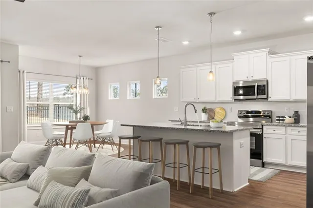 a open kitchen with stainless steel appliances granite countertop a stove a sink a center island a dining table and chairs