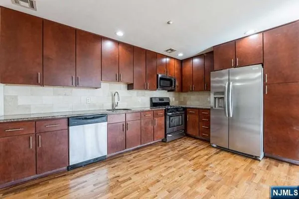 a kitchen with granite countertop wooden cabinets a refrigerator and a sink