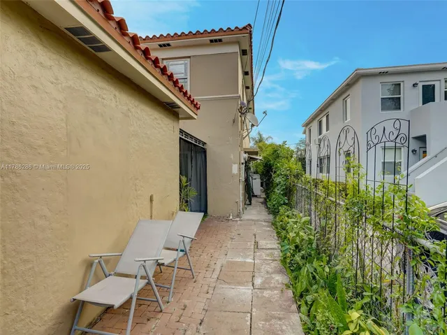 a view of a house with brick walls plants and large tree