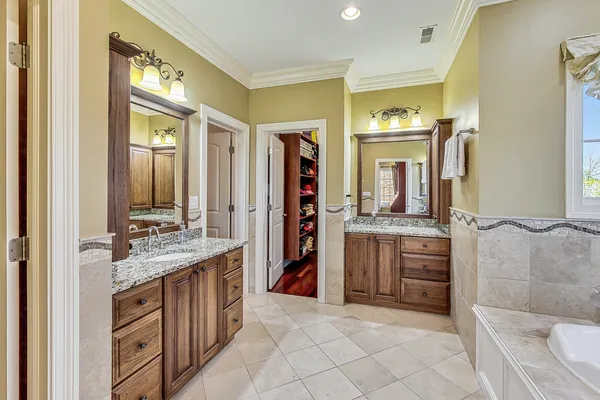 a en suite spacious bathroom with a double vanity sink a mirror and a bathtub