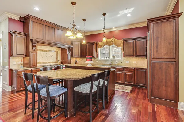a kitchen with stainless steel appliances granite countertop a sink a stove top oven a chimney and a center island
