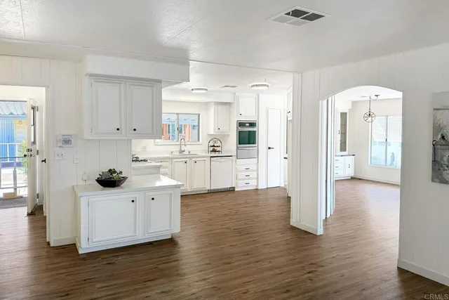 a kitchen with white cabinets and wooden floor