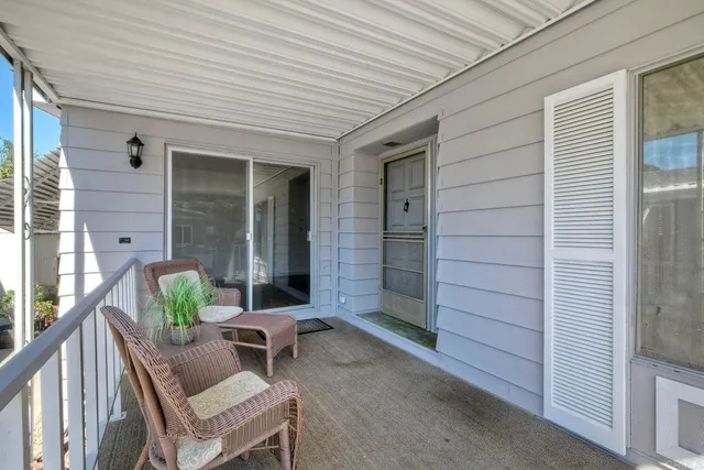 a balcony with couple of chairs and a potted plant