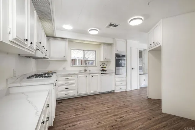 a kitchen with stainless steel appliances white cabinets and wooden floors
