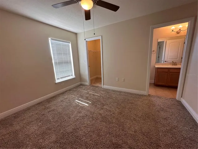 an empty room with a chandelier fan and windows