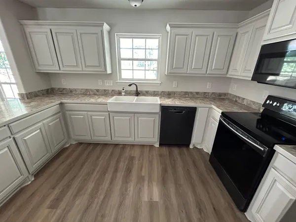 a kitchen with sink a microwave a stove and cabinets