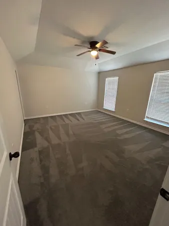 an empty room with windows and fan