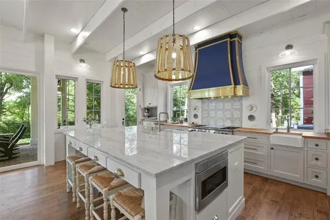 a kitchen with stainless steel appliances granite countertop a sink a stove and a wooden floor